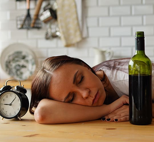 женщина лежит на столе рядом с бутылкой вина