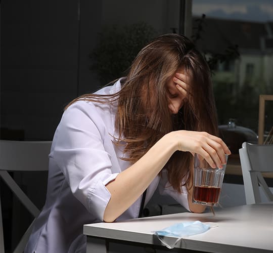 женщина сидит за столом со стаканом алкоголя